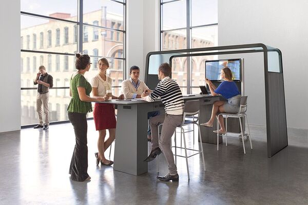 Bright shared workspace with people working at desks and moving around